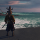 A man with his back to the camera stands looking out at the turquoise waters of a shoreline.